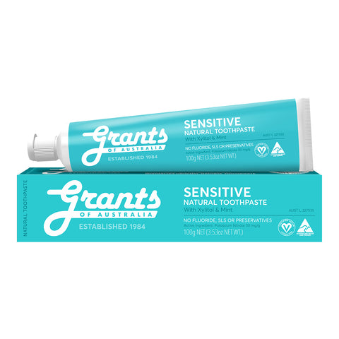A tube of sensitive, natural toothpaste with xylitol and mint placed on its box.