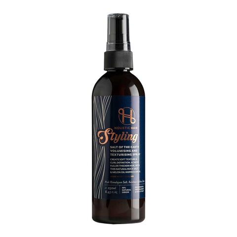 A bottle of Holistic Hair Salt of the Earth Volumising & Texturising Spray with a black label and a spray nozzle on top.