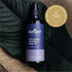 Bottle of Juniper anti-aging revitalizing body oil with a gold award badge on a leafy background