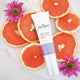 Juniper Antioxidant Skin Firming Serum with grapefruit slices and flowers on a white background