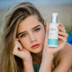 Woman holding a bottle of Juniper Skincare product outdoors