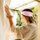 Woman with a pink headband in a greenhouse setting.