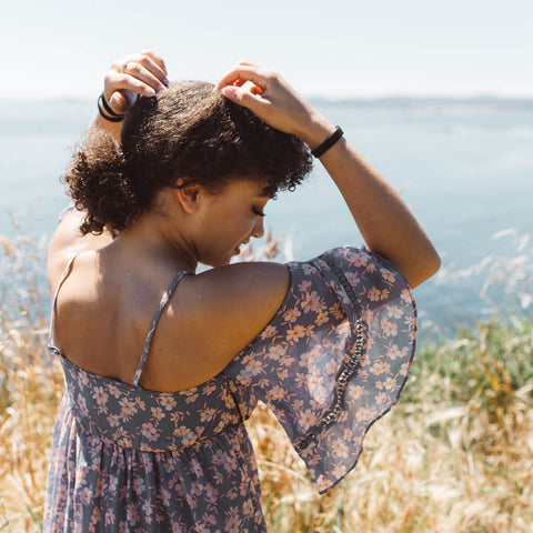 Woman in a floral dress standing in a field with a scenic background