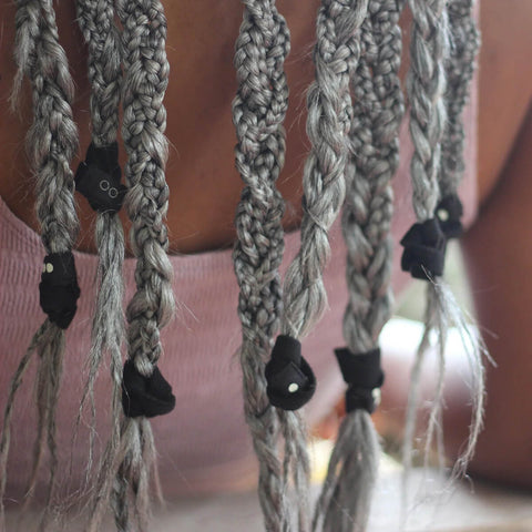 Close-up of braided hair extensions with black clips on a blurred background