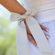 Close-up of a person wearing pale linen clothes with kooshoo's stylish satin bow on her wrist. 