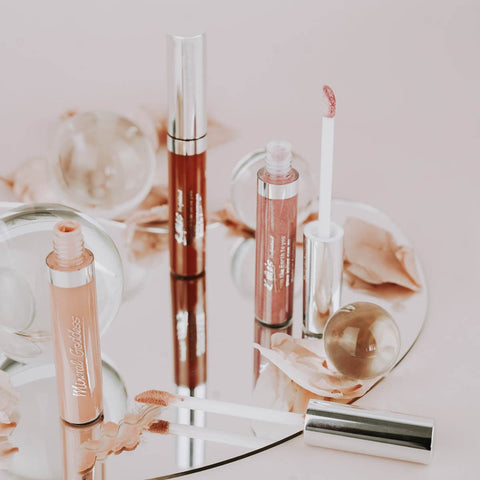 Set of lip glosses on a decorative mirror with floral design