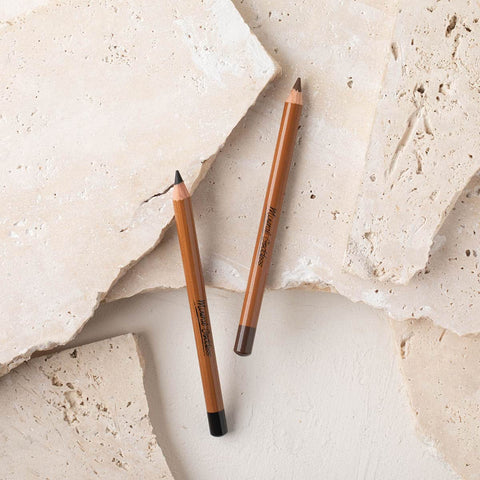 Mineral goddess black and brown pencils laying on a stone background.