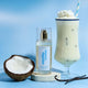 Lavanila Vanilla Coconut 150ml perfume product with a glass of vanilla shake & coconut on a blue background.