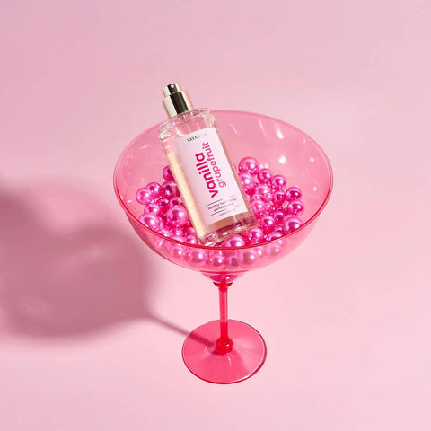 Lavanila Vanilla Grapefruit 150ml bottle in a pink glass with pink pearls on a pink background.