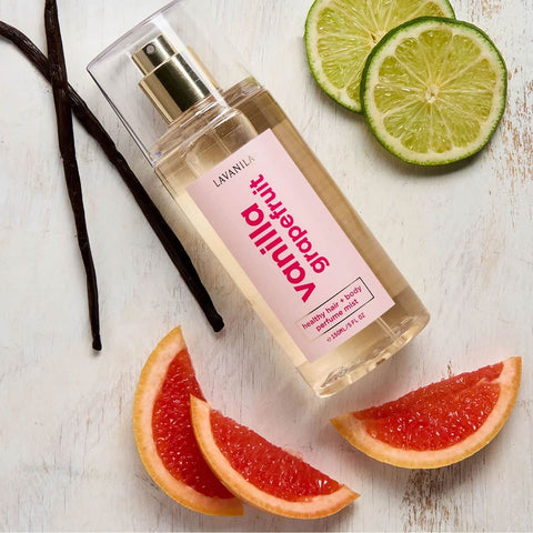 Perfume bottle labeled 'Lavanila Vanilla Grapefruit' with lime, grapefruit, and vanilla beans on a white surface.