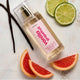 Perfume bottle labeled 'Lavanila Vanilla Grapefruit' with lime, grapefruit, and vanilla beans on a white surface.