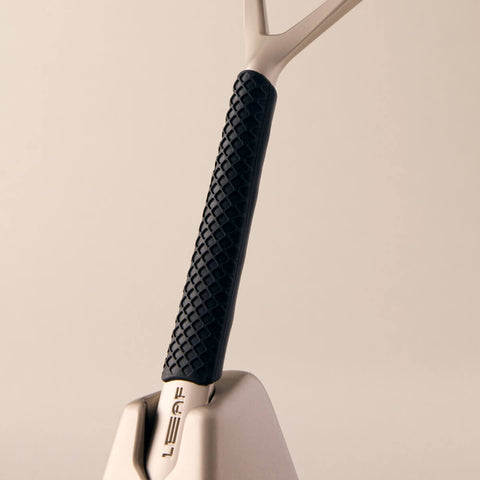 Close-up of a reusable razor with a black textured handle on a beige background