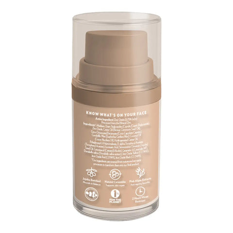 A bottle of tinted sunscreen with a clear outer cylinder casing, a beige pump dispenser, and a beige label showing product information and icons.