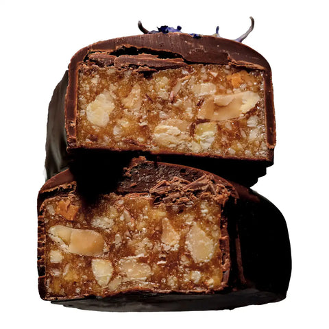 Two stacked chocolate-covered bars with a cut cross-section showing a caramel and almond filling, photographed on a black background.
