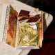 Open packet of Luvio hazelnut truffle bar with luxury packaging, gold foil on a marble surface with red silk in the background.