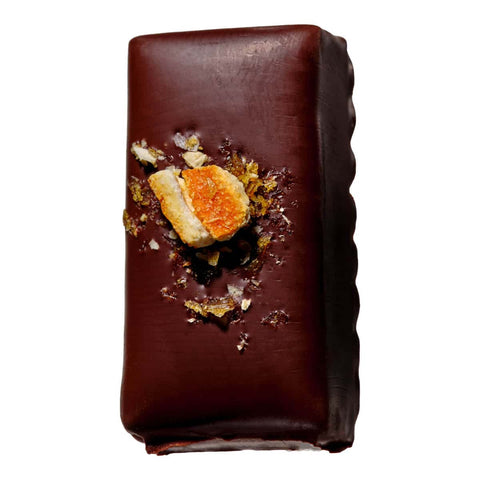 Chocolate covered truffle with ginger pieces and orange peel decoration. 