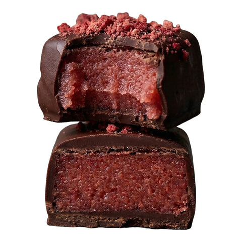 Strawberry vanilla burst chocolate halved and stacked - reddish pink center coated in dark vegan chocolate with freeze dried strawberry sprinkles on top.