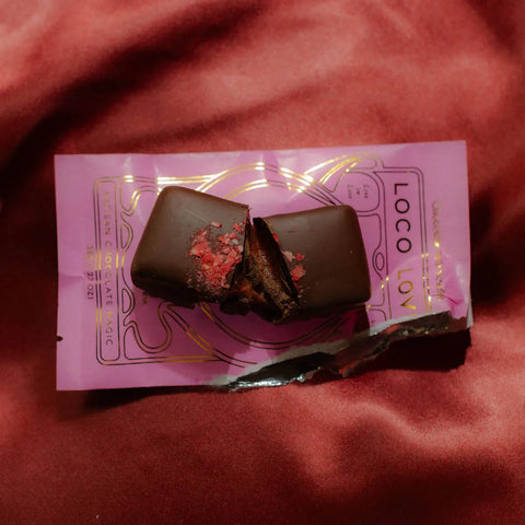 Halved strawberry chocolate, fresh out of the packet on a red silk background