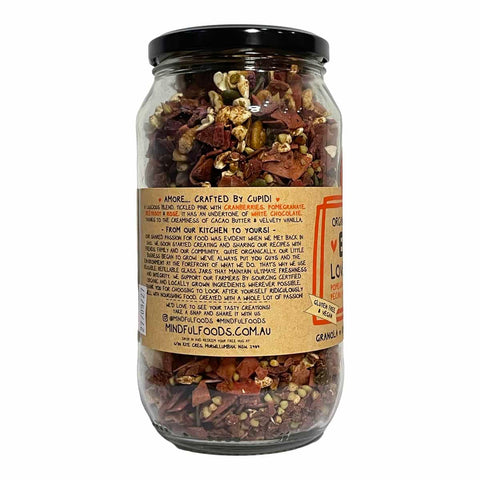 A clear glass jar filled with dried red chili peppers and seeds, sealed with a black lid and featuring a tan paper label on a white background.