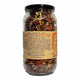 A clear glass jar filled with dried red chili peppers and seeds, sealed with a black lid and featuring a tan paper label on a white background.