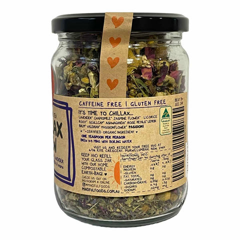 A glass jar of Mindful Foods 'It's Time to Chillax' herbal tea blend, featuring a black lid, a kraft paper label with text and a small orange heart graphic, and dried herbs visible inside.