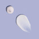 Two droplets of white cream on a light purple background.