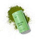 Green container of Matcha Latte powder with matcha powder scattered around on a white background