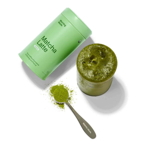 Matcha latte powder in a green container with a scoop of powder on a white background