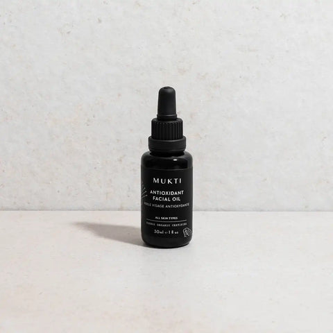 MUKTI facial oil dropper bottle styled on a stone surface and background.