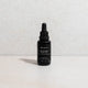 MUKTI facial oil dropper bottle styled on a stone surface and background.