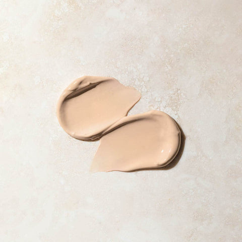 Swatch of daily moisturiser on a beige marbled surface.