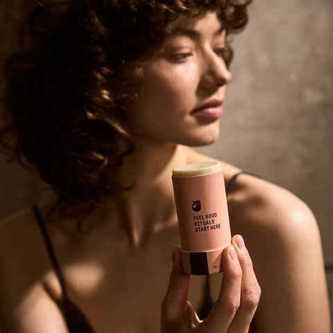 Woman holding a Papermoon Clean Deodorant - Unscented 75g product with text against a neutral background.