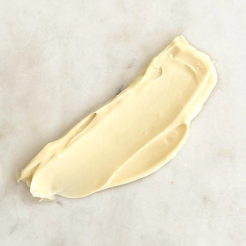 Swatch of thick creamy replenish moisturiser on a marble surface.
