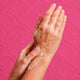Hands with soap bubbles against a pink patterned background.