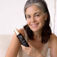 Woman holding Retreatment Botanics Collagen Calm Activated Mist 100ml product with a neutral background.