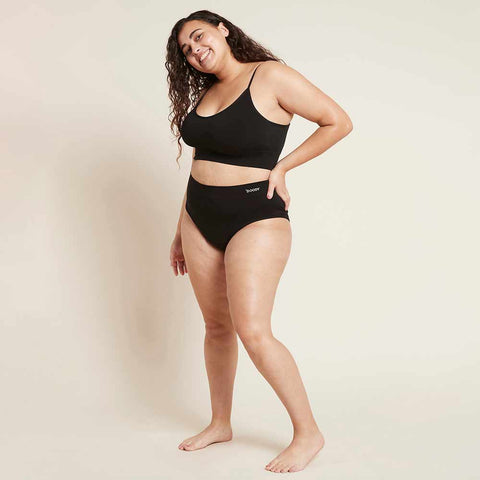 Boody Period Full Brief Light-Moderate lifestyle shot of a woman with long dark hair, hand on hip, in a black bra top and full brief