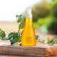 Yellow bottle with a spray nozzle on a stone surface with green leaves in the background