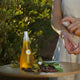 Person applying a spray bottle of yellow liquid to their arm outdoors.