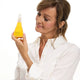 Woman holding a bottle of yellow jojoba oil against a white background