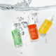 Three bottles of The Jojoba Company skincare products with water droplets and splashes.