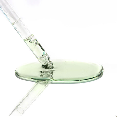 Glass dropper with a green clear liquid on a white background