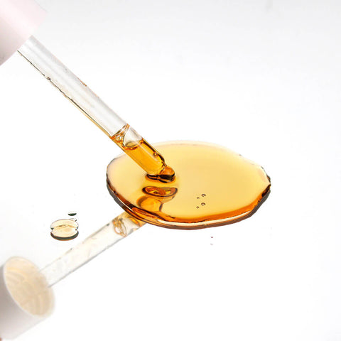 Glass dropper with amber liquid on a white background.