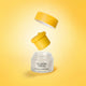 A jar of The Jojoba Company Jojoba Intense Moisture Balm with its yellow lid floating above it against a yellow gradient background.