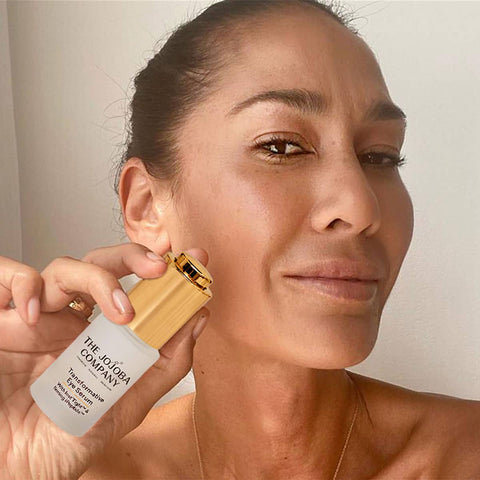 Woman holding The Jojoba Company Transformative Eye Serum to her face.