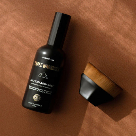 'Three Warriors face tan aqua mist' bottle with a brush on a brown background.