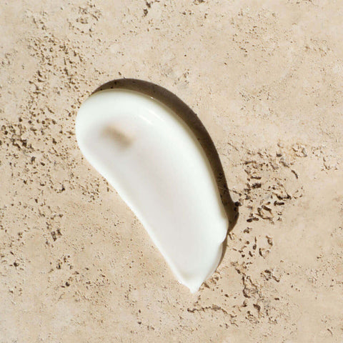 White cream smear on a beige textured background.