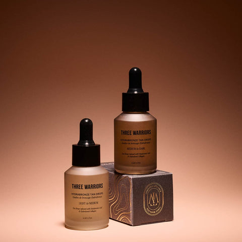 Two bottles of 'Three Warriors' tanning products on a brown background