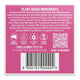 The back of a product box showing a pink panel with ingredient list text, certification icons, a QR code, and a barcode.