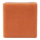 A single square bar of orange soap with a textured surface, isolated on a white background.