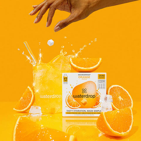 waterdrop Microdrink - Orange hydration package with oranges & a glass on an orange background.